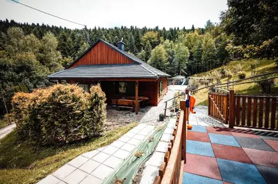 a small building with a porch next to a forest at Świerkowe Zacisze Domki in Budzów