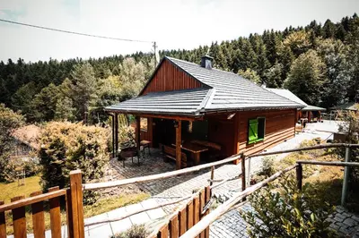 a log cabin with a porch and a fence at Świerkowe Zacisze Domki in Budzów