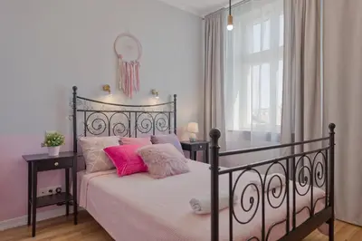 a bedroom with a black bed with pink pillows at Centre Apartments-Old Town in Kraków