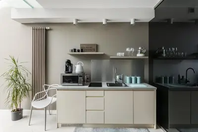 a kitchen with white cabinets and a sink and a chair at A11 Apartments & SPA Dermique in Kraków