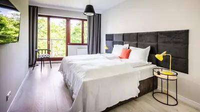 a bedroom with a large bed with white sheets and orange pillows at A11 Apartments & SPA Dermique in Kraków