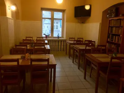 a dining room with tables and chairs and a window at Dom Franciszkański San Antonio in Kraków