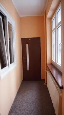 an empty hallway with a door and two windows at Dom Franciszkański San Antonio in Kraków