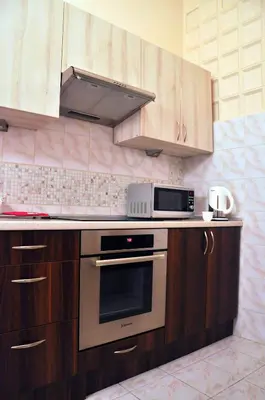 a kitchen with wooden cabinets and a microwave at Dom Franciszkański San Antonio in Kraków