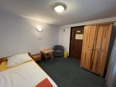 a bedroom with a bed and a desk and a chair at Dom Franciszkański San Antonio in Kraków