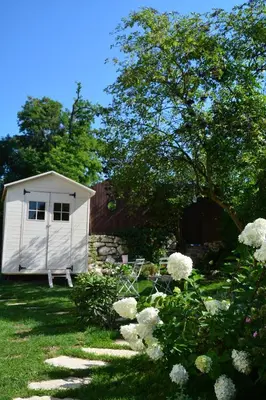 a small white shed in a yard with white flowers at Leśna 6 - House with a garden in Bolechowice