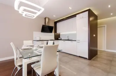 a kitchen and dining room with a glass table and white chairs at Old Town Luxury Apartments in Kraków