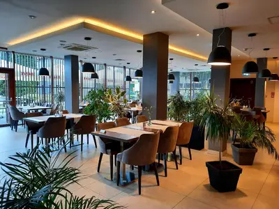 a restaurant with wooden tables and chairs and plants at Hotel Imperiale in Oświęcim