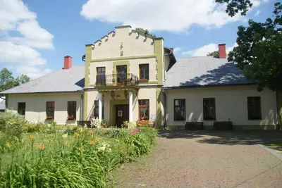 a large white house with a garden in front of it at Dworek Młynarza in Zator