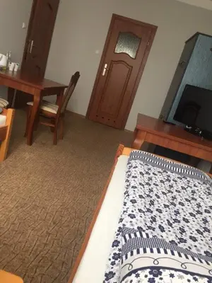 a bedroom with a bed and a table and a television at Dworek Młynarza in Zator