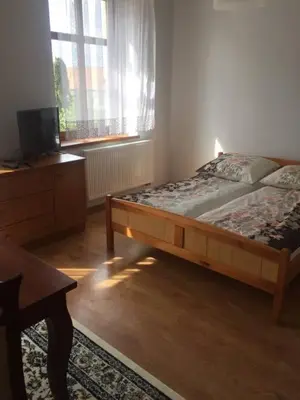 a bedroom with a bed and a dresser and a television at Dworek Młynarza in Zator