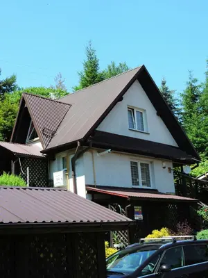 a house with a roof with a car parked in front at Apartament Suzyw Kicek in Sucha Beskidzka