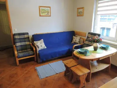 a living room with a blue couch and a table at Apartament Suzyw Kicek in Sucha Beskidzka