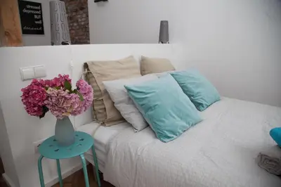 a bed with a vase of flowers on a table at Venice Lagoon Apartment in Kraków