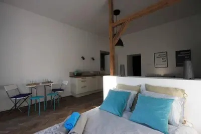 a bedroom with a bed with blue pillows and a kitchen at Venice Lagoon Apartment in Kraków