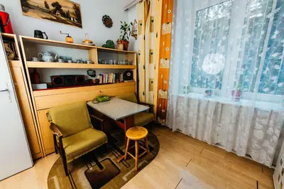 a small table and chair in a room with a window at Feel The Old Socialist Style Apartment in Kraków