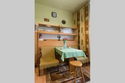 a dining room with a table and chairs and a clock at Feel The Old Socialist Style Apartment in Kraków