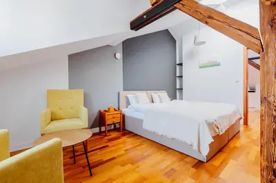 a bedroom with a bed and a chair at Atticus Apartments in Kraków