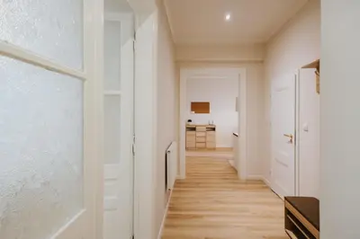 a hallway with white walls and wood floors at Atticus Apartments in Kraków