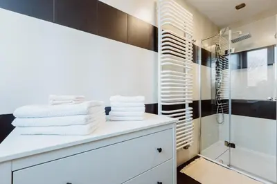 a bathroom with white towels on a counter and a shower at Atticus Apartments in Kraków