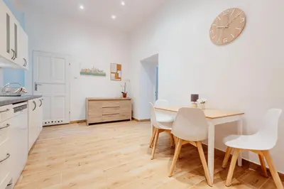 a kitchen with a table and chairs and a clock on the wall at Atticus Apartments in Kraków