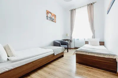 a bedroom with two beds and a chair at Atticus Apartments in Kraków