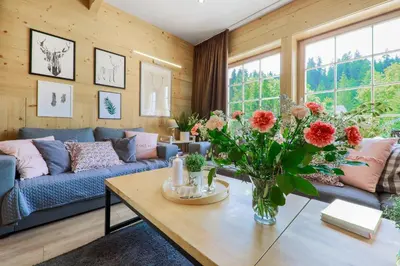 a living room with a couch and a table with flowers at Domek nad Potokiem in Nowy Targ