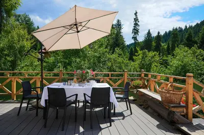 a table with chairs and an umbrella on a deck at Domek nad Potokiem in Nowy Targ