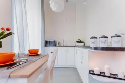 a kitchen with white cabinets and a table with candles at Garden Apartment in Kraków