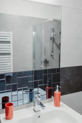 a bathroom with a sink with a mirror and a shower at Garden Apartment in Kraków