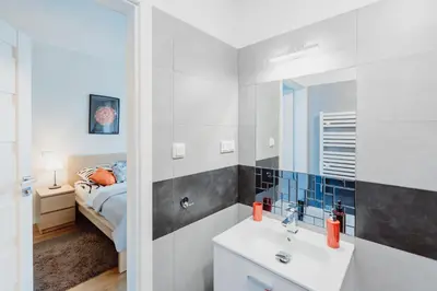 a bathroom with a sink and a mirror and a bed at Garden Apartment in Kraków