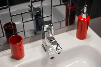 a bathroom sink with a faucet and two red cups at Garden Apartment in Kraków