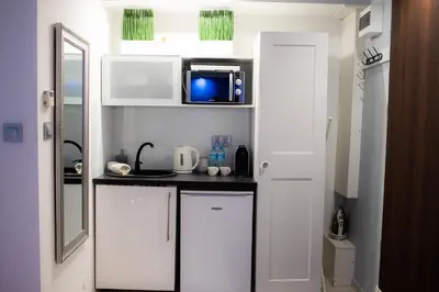 a small kitchen with white cabinets and a microwave at Jacuzzi Apartment Zen in Kraków