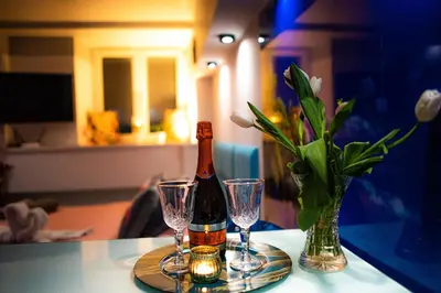 a bottle of champagne and two glasses on a table at Jacuzzi Apartment Zen in Kraków