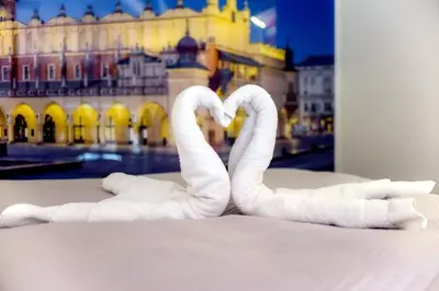 two white towel swans are sitting on the floor at Apartment Brzozowa in Kraków