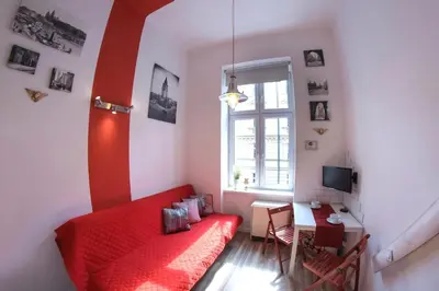 a small bedroom with a red bed and a desk at Apartment Brzozowa in Kraków