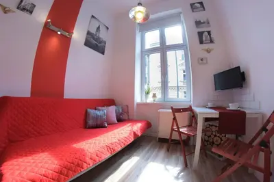 a living room with a red couch and a desk at Apartment Brzozowa in Kraków