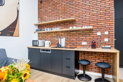 a kitchen with a counter with stools and a brick wall at Cracow Rentals Zacisze in Kraków