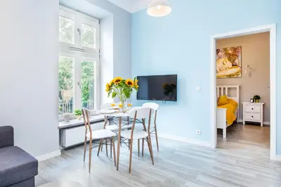 a white living room with a table and chairs at Cracow Rentals Zacisze in Kraków