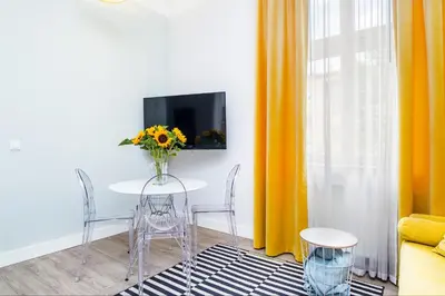 a living room with a table with a vase of flowers at Cracow Rentals Zacisze in Kraków