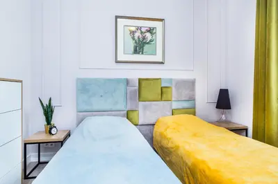 a bedroom with two beds and a painting on the wall at Cracow Rentals Zacisze in Kraków