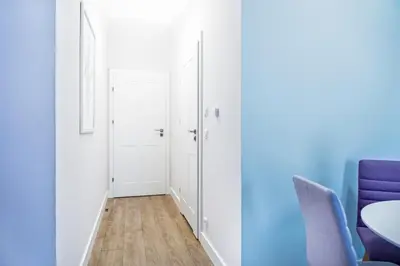 a hallway with blue walls and a table and chairs at Cracow Rentals Zacisze in Kraków