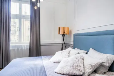 a bedroom with a bed with a blue headboard and a window at Cracow Rentals Zacisze in Kraków