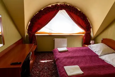 a bedroom with a bed and a window with curtains at Hotel Zajazd Celtycki in Zakrzów
