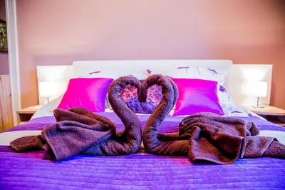two swans are forming a heart on a bed at Market Square Residence in Kraków