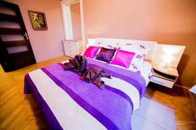 a bedroom with a large bed with pink and purple sheets at Market Square Residence in Kraków