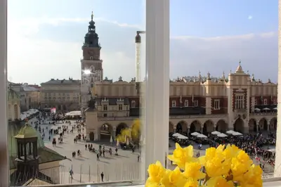 a view of a city from a window with yellow flowers at Market Square Residence in Kraków