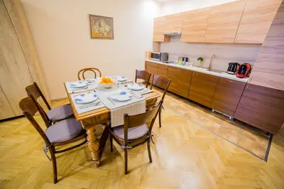 a dining room with a table and chairs and a kitchen at Market Square Residence in Kraków