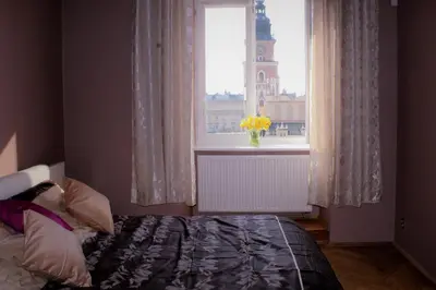 a bedroom with a bed and a window with a tower at Market Square Residence in Kraków