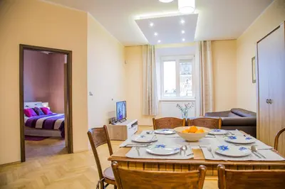 a dining room with a table and chairs and a living room at Market Square Residence in Kraków